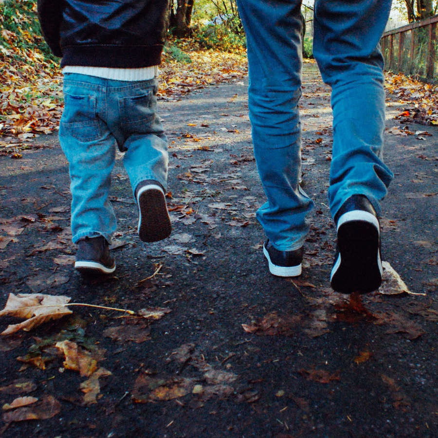 Young boy and an Adult walking through the woods in Fall