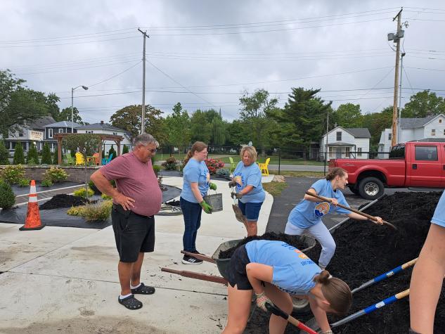 group of people getting mulch from a large pile