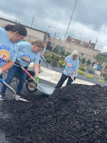 group of people getting mulch from a large pile