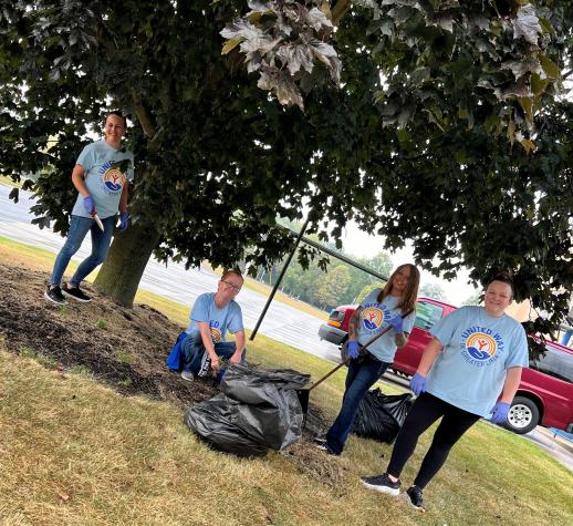 Group of people spreading mulch under a tree