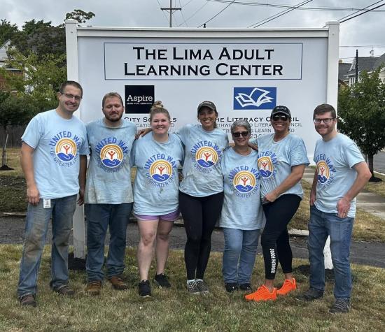 Group of people in blue United Way shirts in front of the lima adult learning center sign