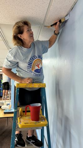 woman on ladder painting a wall blue