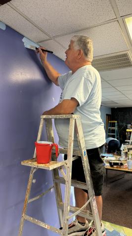 Man on ladder painting a wall