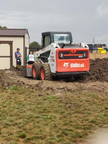 Construction bobcat removing dirt from a hill to level it